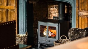A room with a stone fireplace, a blue mantelpiece, and a modern wood-burning stove. - Seckford Hall Hotel & Spa (Woodbridge)
