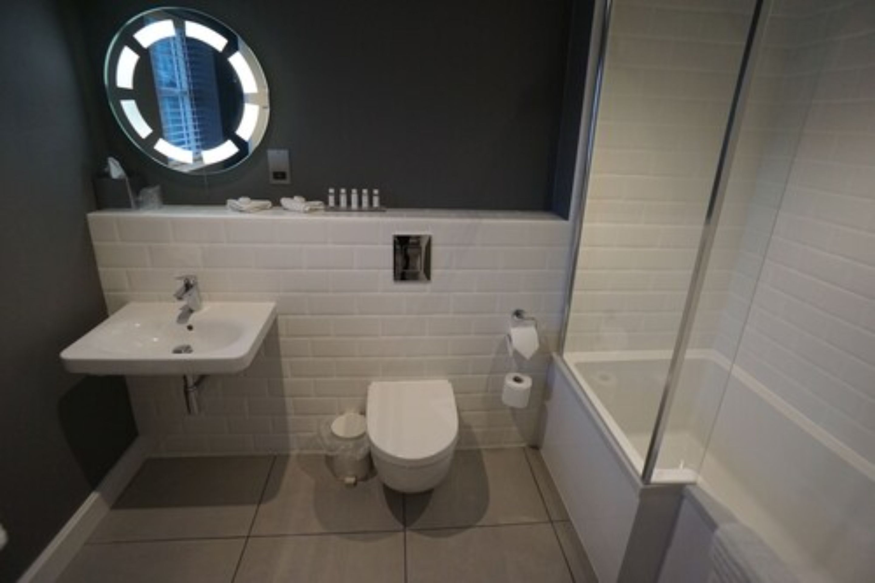 Een kleine badkamer met een wit wastafel, toilet en een douchecabine van glas.