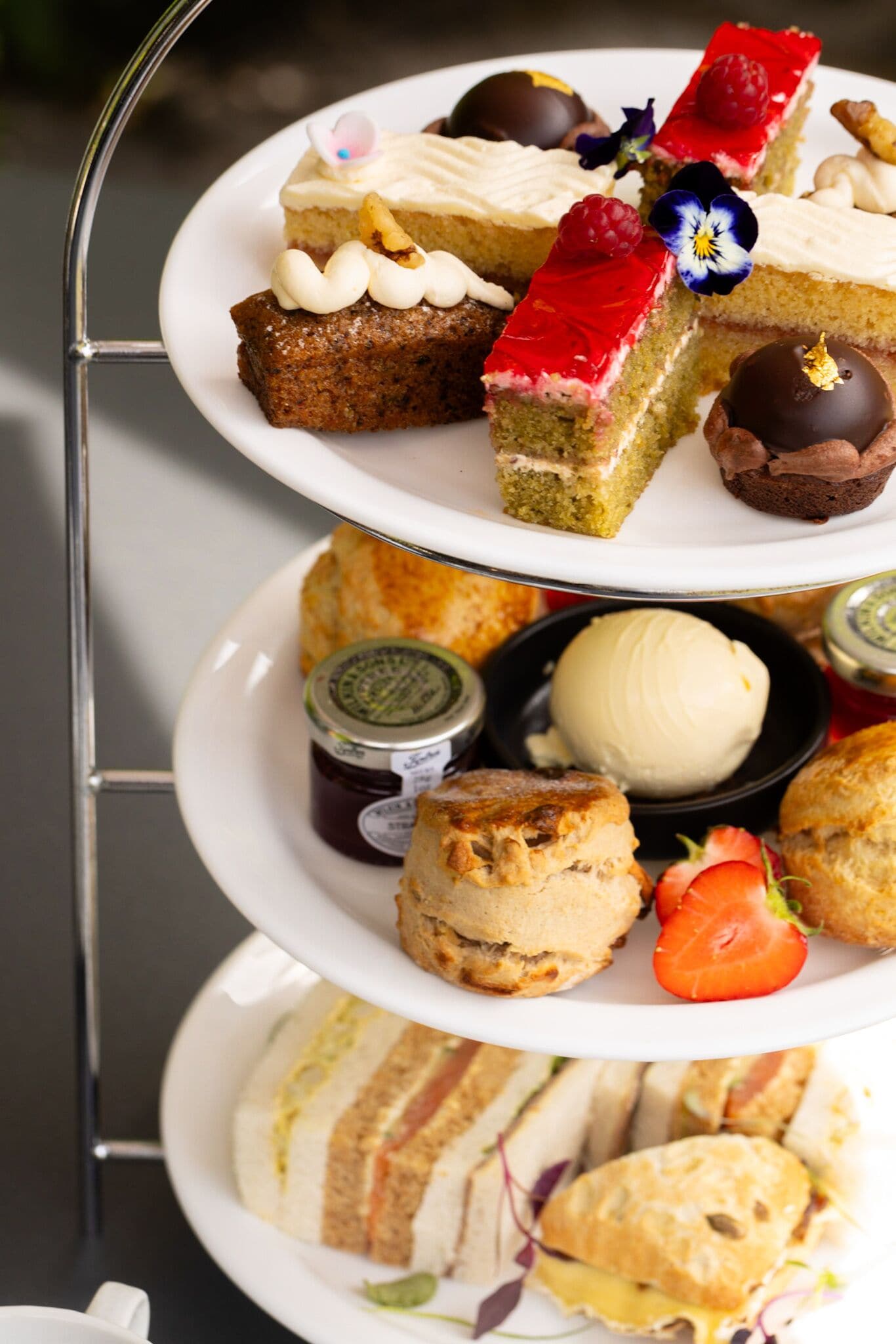 A three-tiered dessert display with various pastries and desserts.