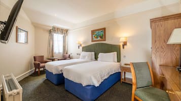 Hotelkamer met twee bedden, een bureau, een stoel, een televisie en een schilderij aan de muur.