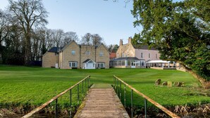 A large stone building with a grassy lawn and a wooden bridge leading to it. - Hall Garth Hotel Darlington, Sure Hotel Collection by BW (Darlington)