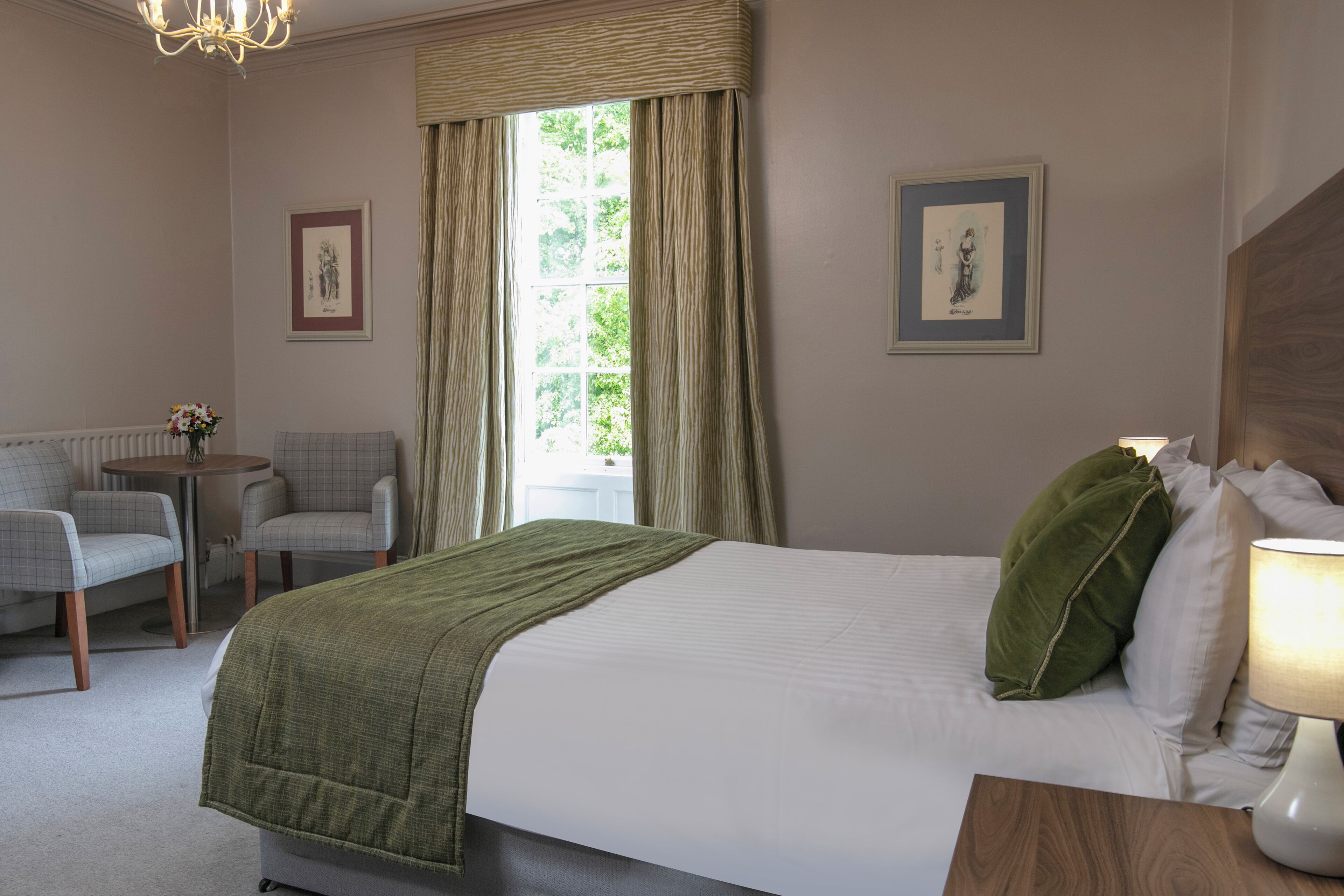 Una habitación de hotel con una cama, una silla, una mesita y una lámpara.