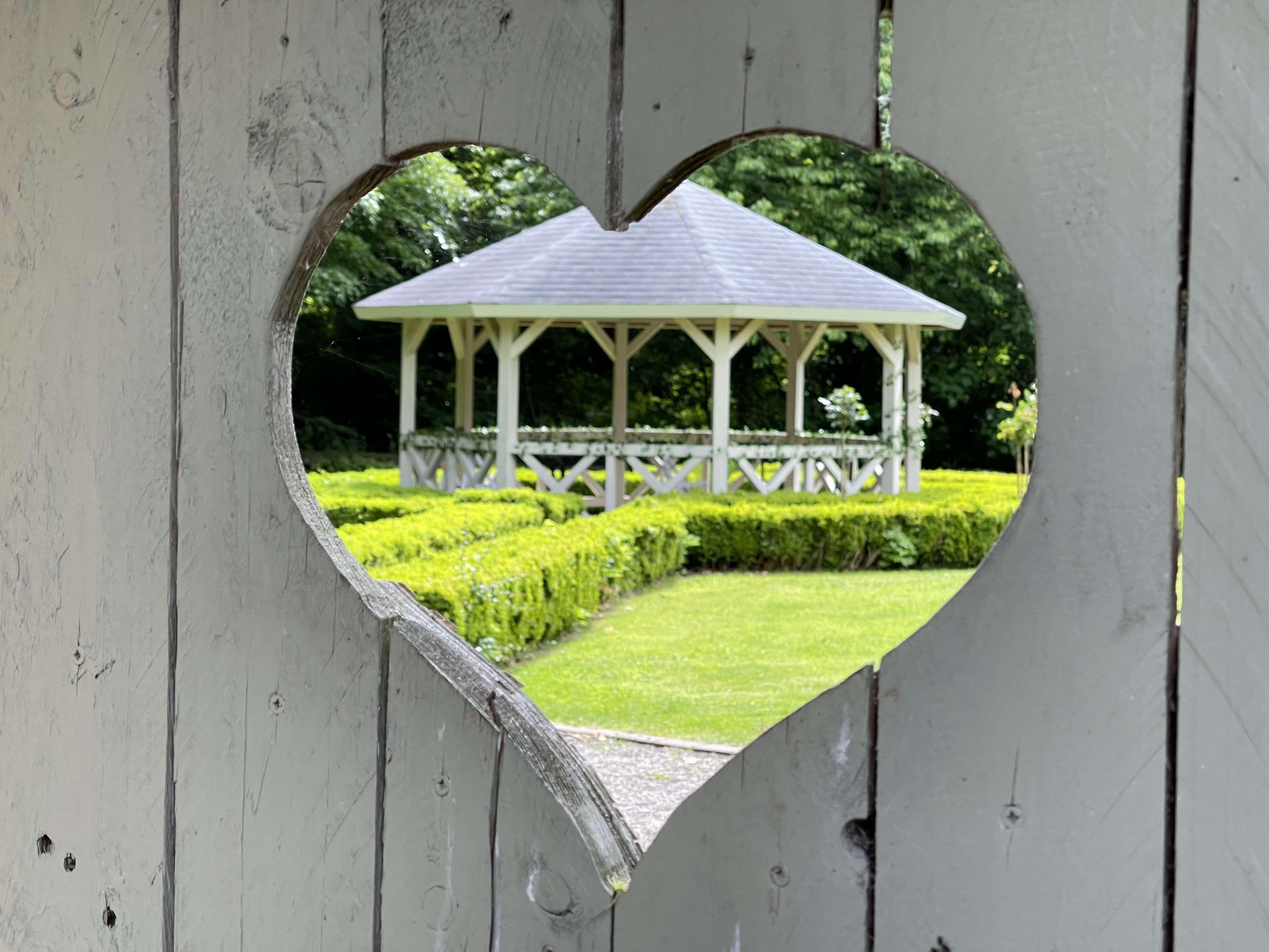A heart-shaped window with a gazebo in the background.