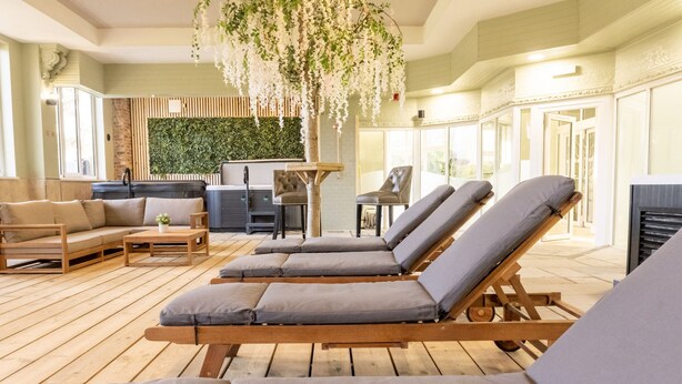A sunlit lounge area with wooden flooring, cushioned lounge chairs, a sofa, and a small table. - Hall Garth Hotel Darlington, Sure Hotel Collection by BW (Darlington)