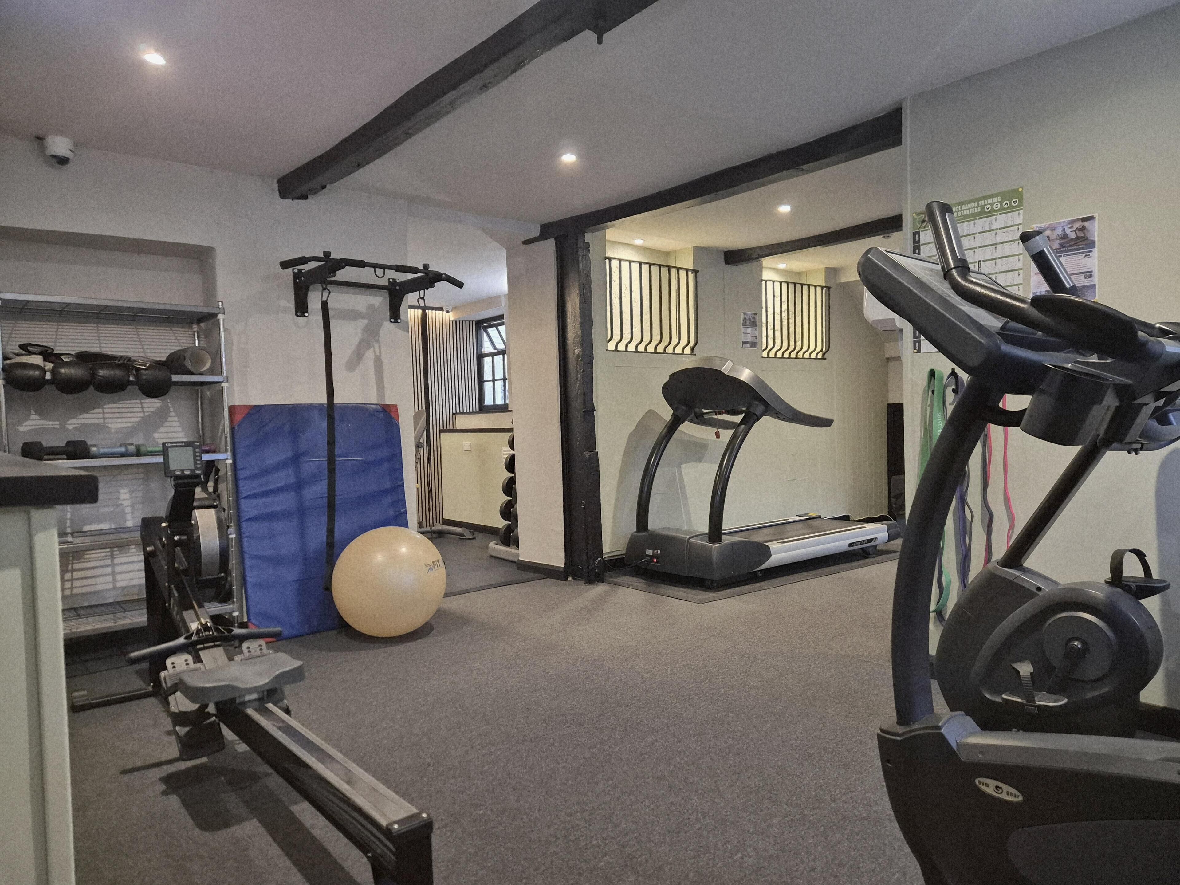 A gym with treadmills, a rowing machine, a bench press, and a large exercise ball.