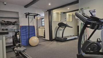 A gym with treadmills, a rowing machine, a bench press, and a large exercise ball.