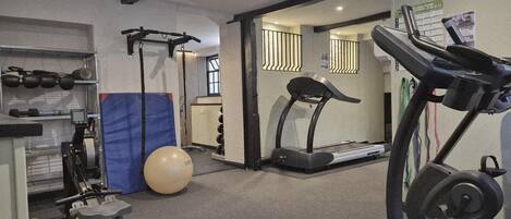 A gym with treadmills, a rowing machine, a bench press, and a large exercise ball.