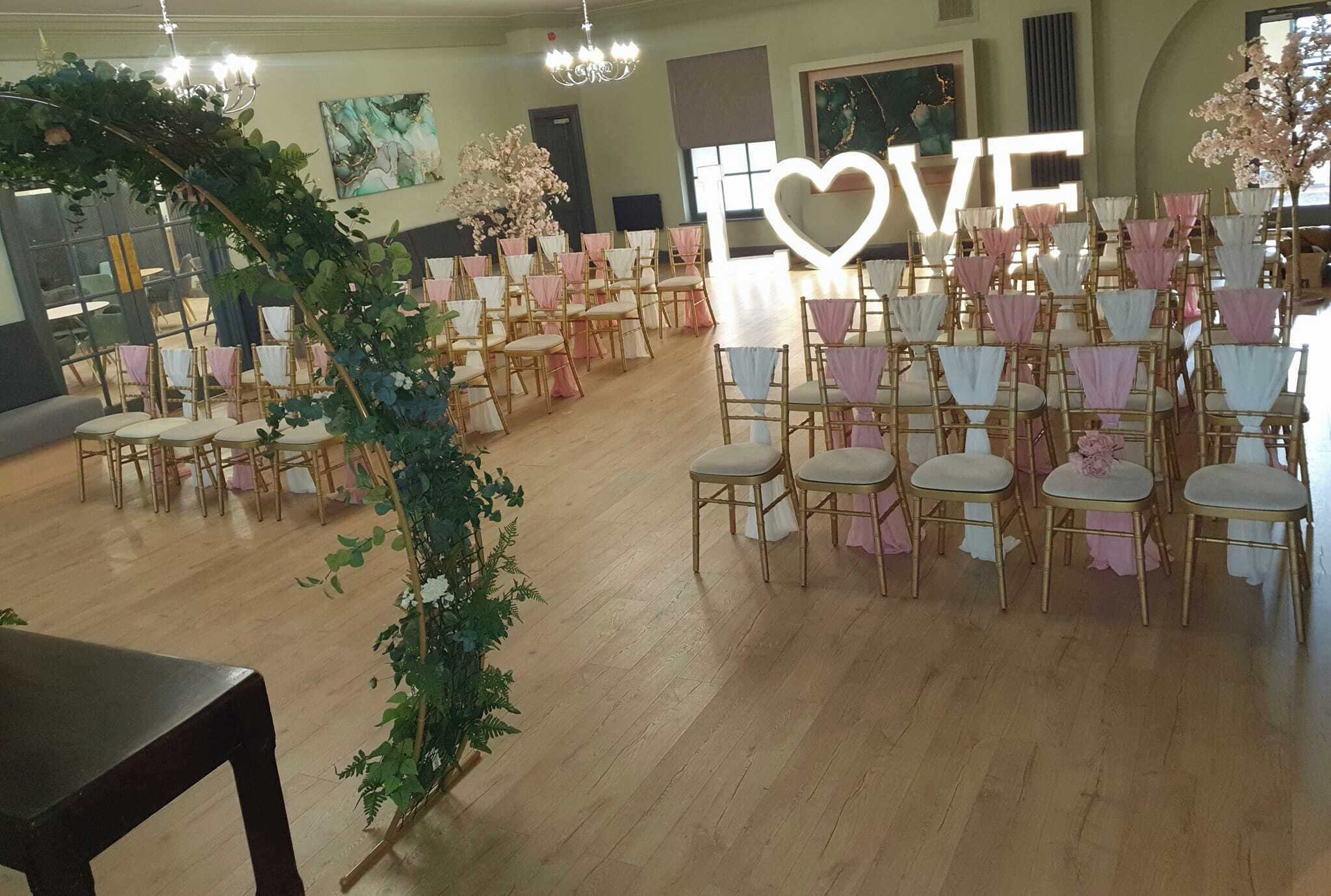 A room with rows of chairs, a large 'LOVE' sign, and a chandelier.