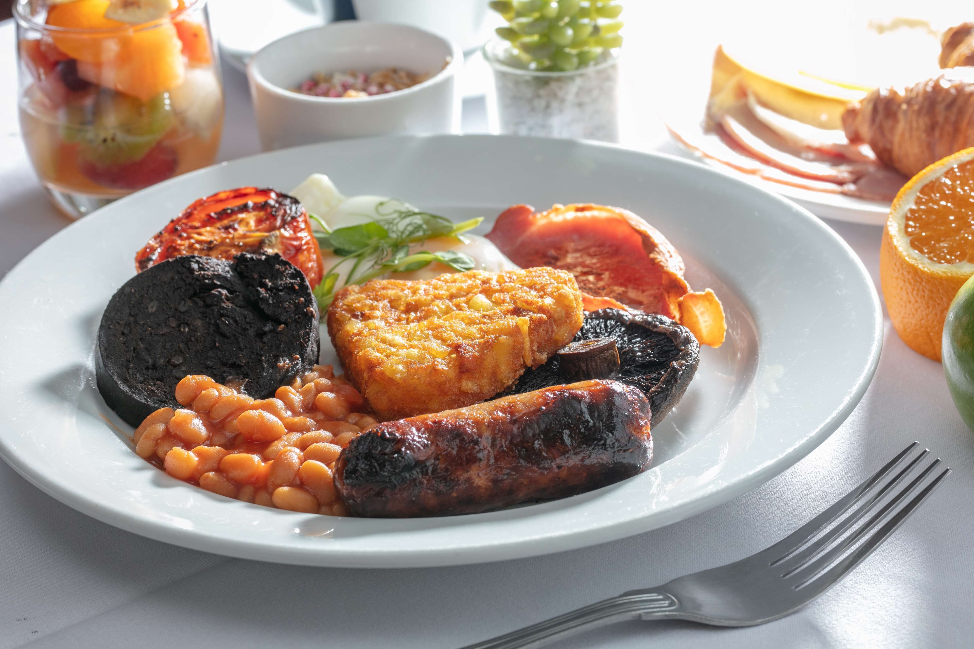 A plate of food with beans, sausages, and a grilled tomato.