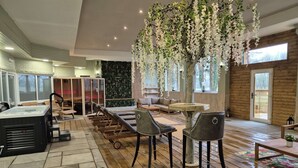 A spacious indoor area with a hot tub, lounge chairs, a wooden table, and a large hanging plant. - Hall Garth Hotel Darlington, Sure Hotel Collection by BW (Darlington)