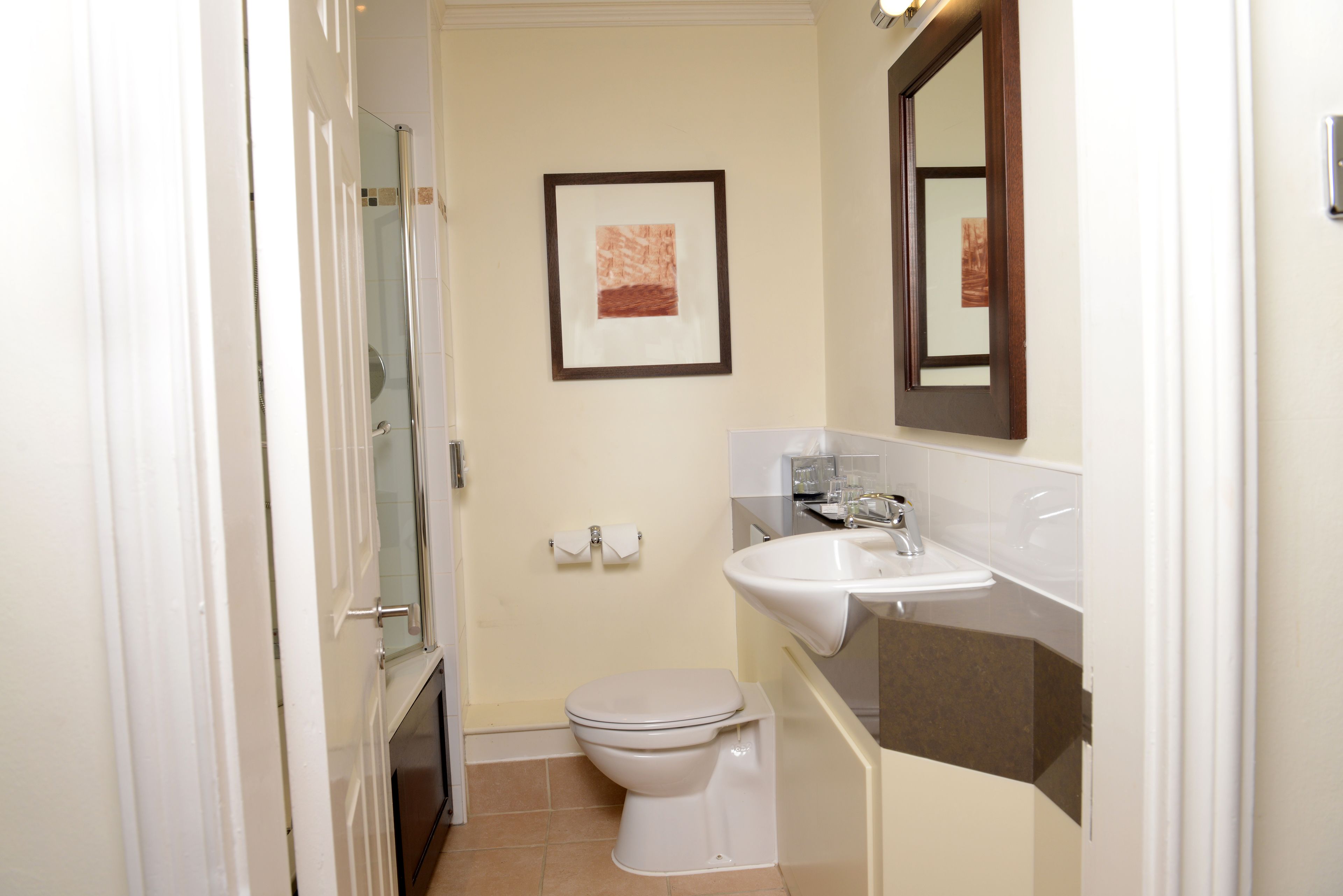 Un baño pequeño con inodoro, lavamanos y ducha.