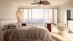 A modern hotel room with a large bed, a ceiling fan, a TV, and a view of the city through large windows. - Marina Resort - Adults Only (Nelson Bay)