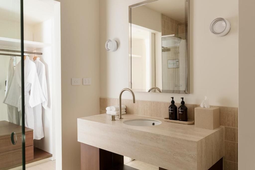 A modern bathroom with a beige countertop, a sink, a mirror, and a glass shower enclosure.