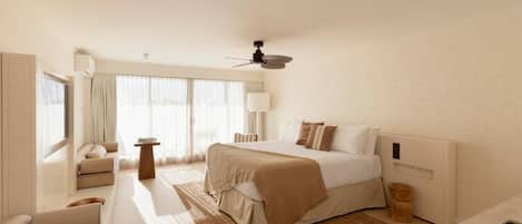 A modern hotel room with a large bed, a sofa, a small table, and a ceiling fan.