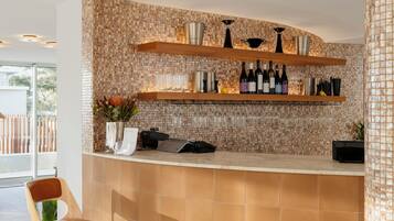 A modern bar area with a curved counter, wooden shelves, and a patterned wall.