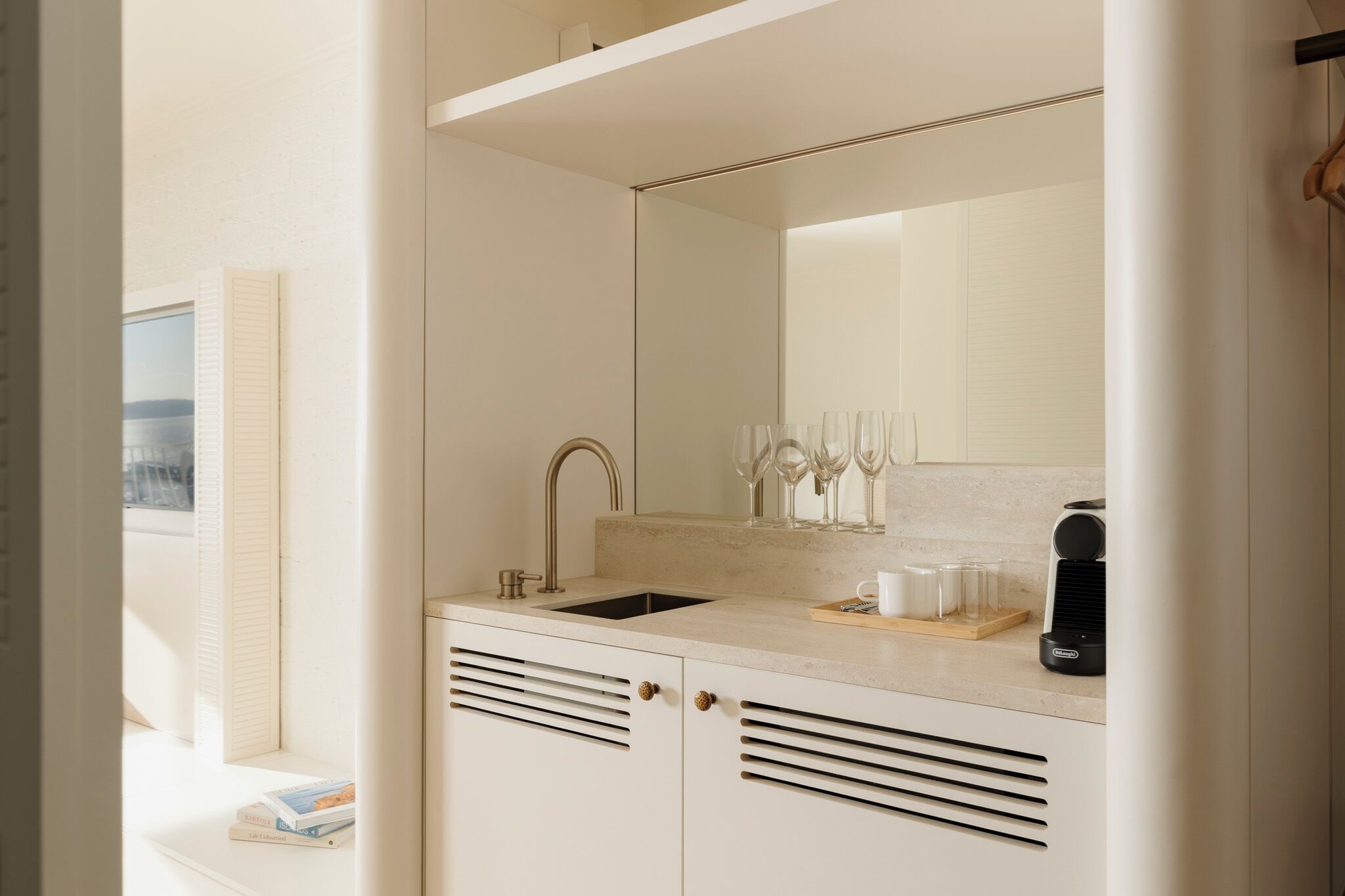 A modern bathroom with a sink, mirror, and ventilation slats.