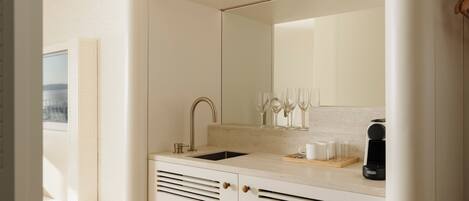 A modern bathroom with a sink, mirror, and ventilation slats.