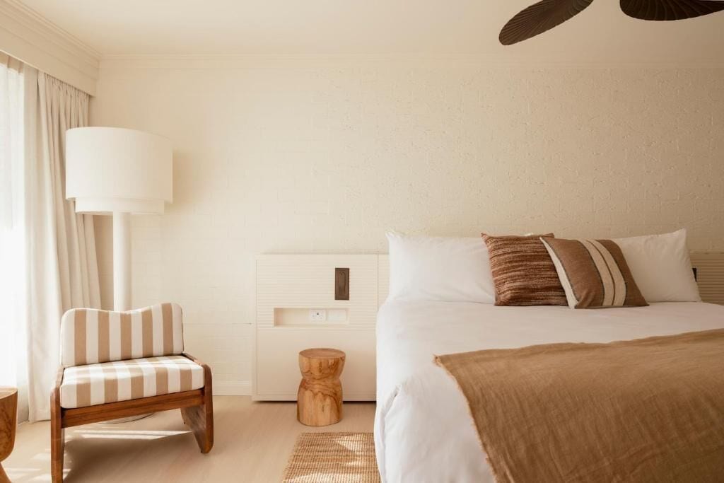 A bedroom with a bed, a chair, a nightstand, and a lamp.