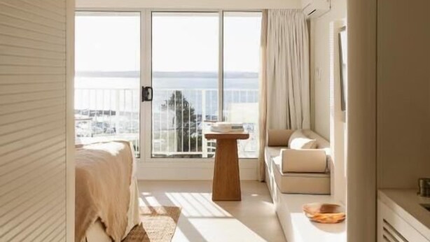 A modern hotel room with a large balcony, a bed, a seating area, and a small table. - Marina Resort - Adults Only (Nelson Bay)