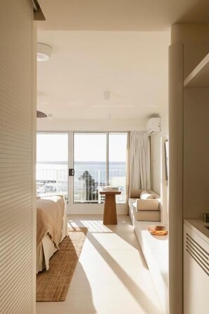 A modern hotel room with a large balcony, a bed, a seating area, and a small table. - Marina Resort - Adults Only (Nelson Bay)