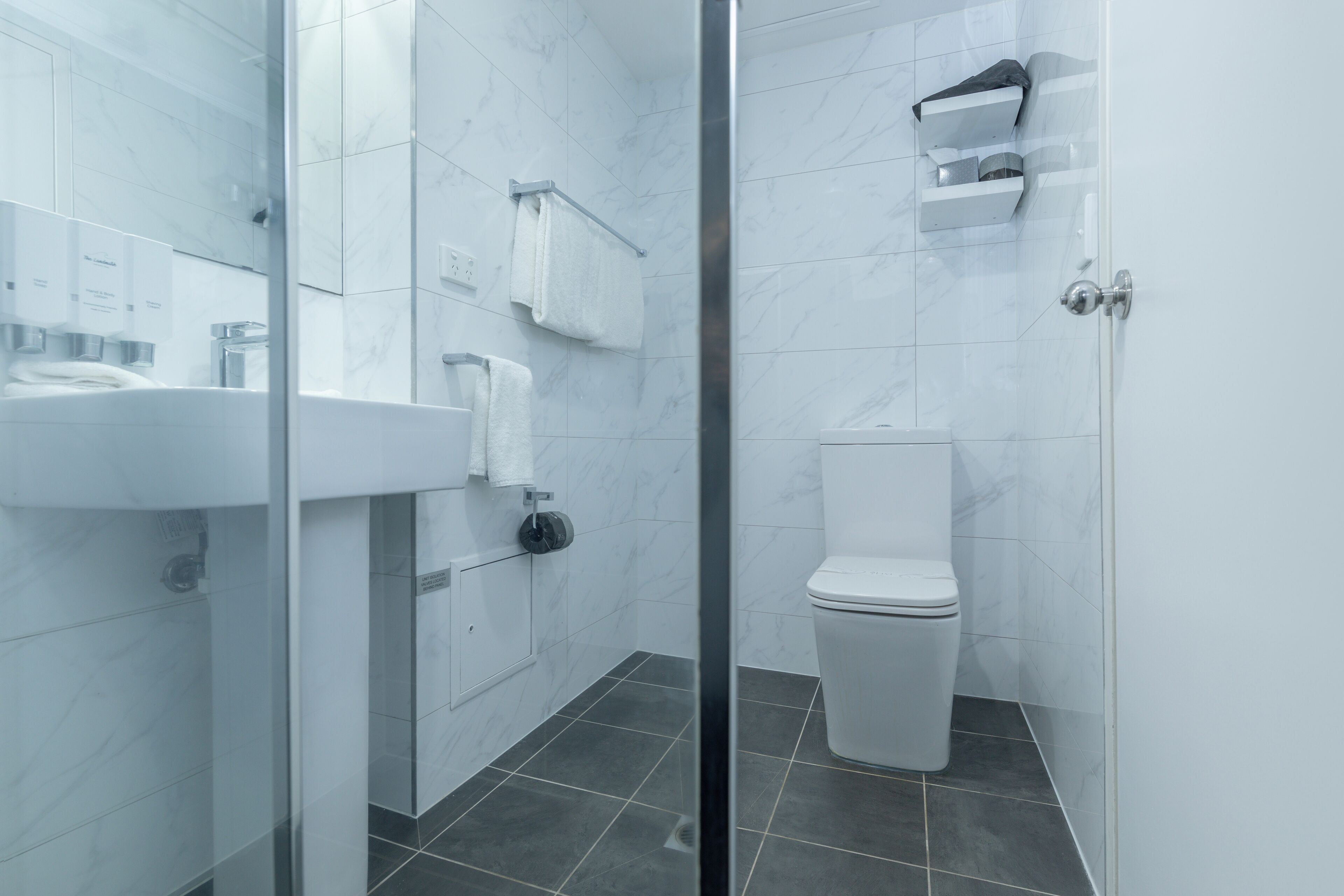 Ein modernes Badezimmer mit Duschkabine aus Glas, einem weißen Waschbecken und einer Toilette.