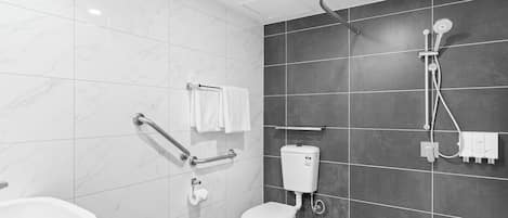 Une salle de bain moderne équipée de toilettes, de barres d’appui, d’une douche et d’un lavabo.