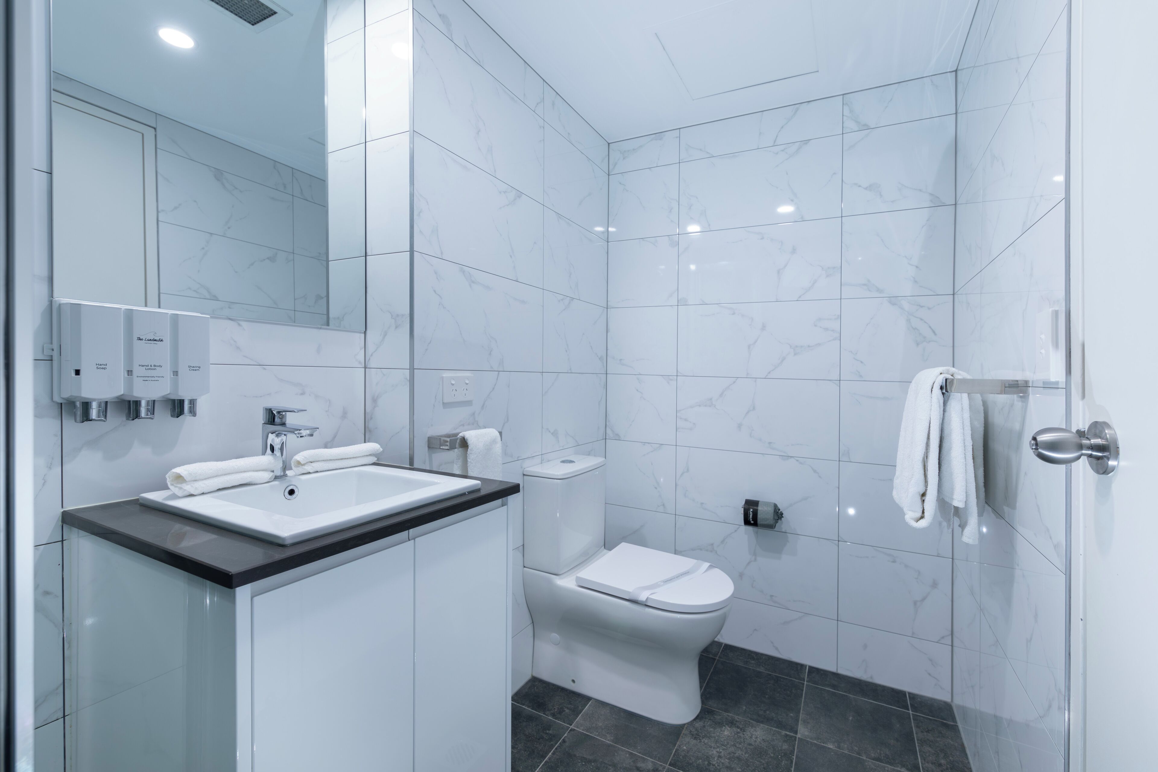 Un baño moderno con lavamanos, inodoro y ducha blancos.