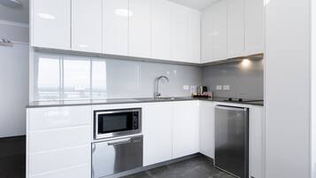 A modern kitchen with white cabinets, a built-in microwave, a dishwasher, and a refrigerator.