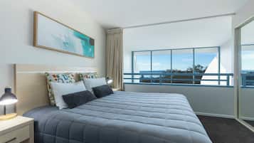 Une chambre d’hôtel moderne, dotée d’un grand lit, d’une table de chevet, d’un bureau et d’une fenêtre donnant sur la ville.