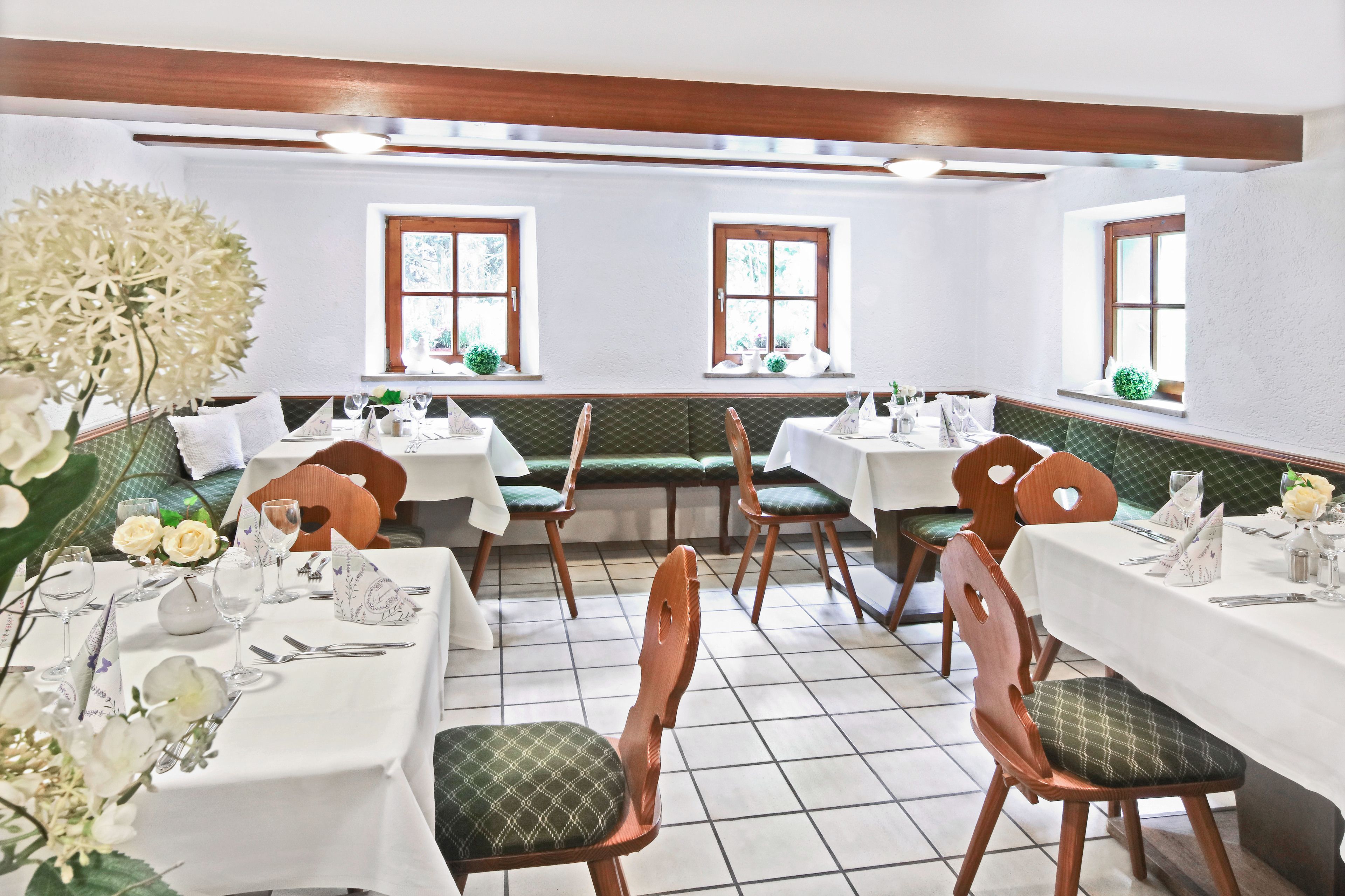 Un restaurant amb seients a boxes i taules, caires de fusta i tovallons blancs.