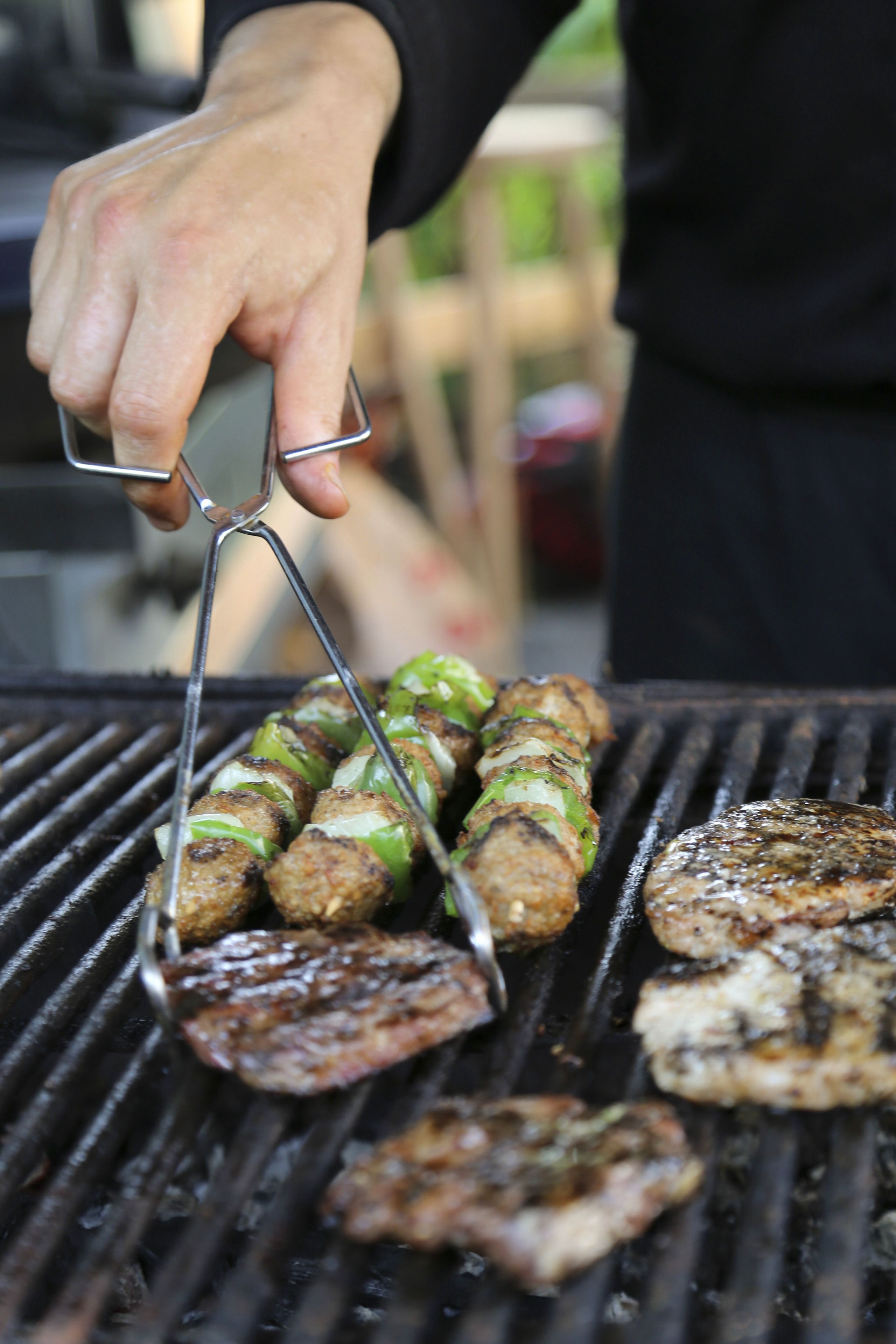 Una persona asando carne en una parrilla al aire libre.