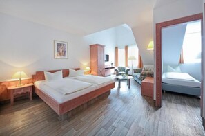 Une chambre spacieuse avec un grand lit, une armoire en bois, une petite table et un canapé.