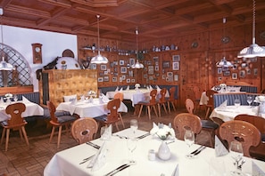 A restaurant with wooden paneled walls, white tablecloths, and wooden chairs. - Waldhotel Bächlein (Mitwitz)