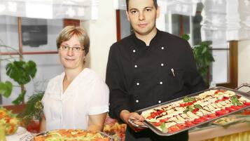 Two individuals holding trays of food, likely at a buffet or catering event.