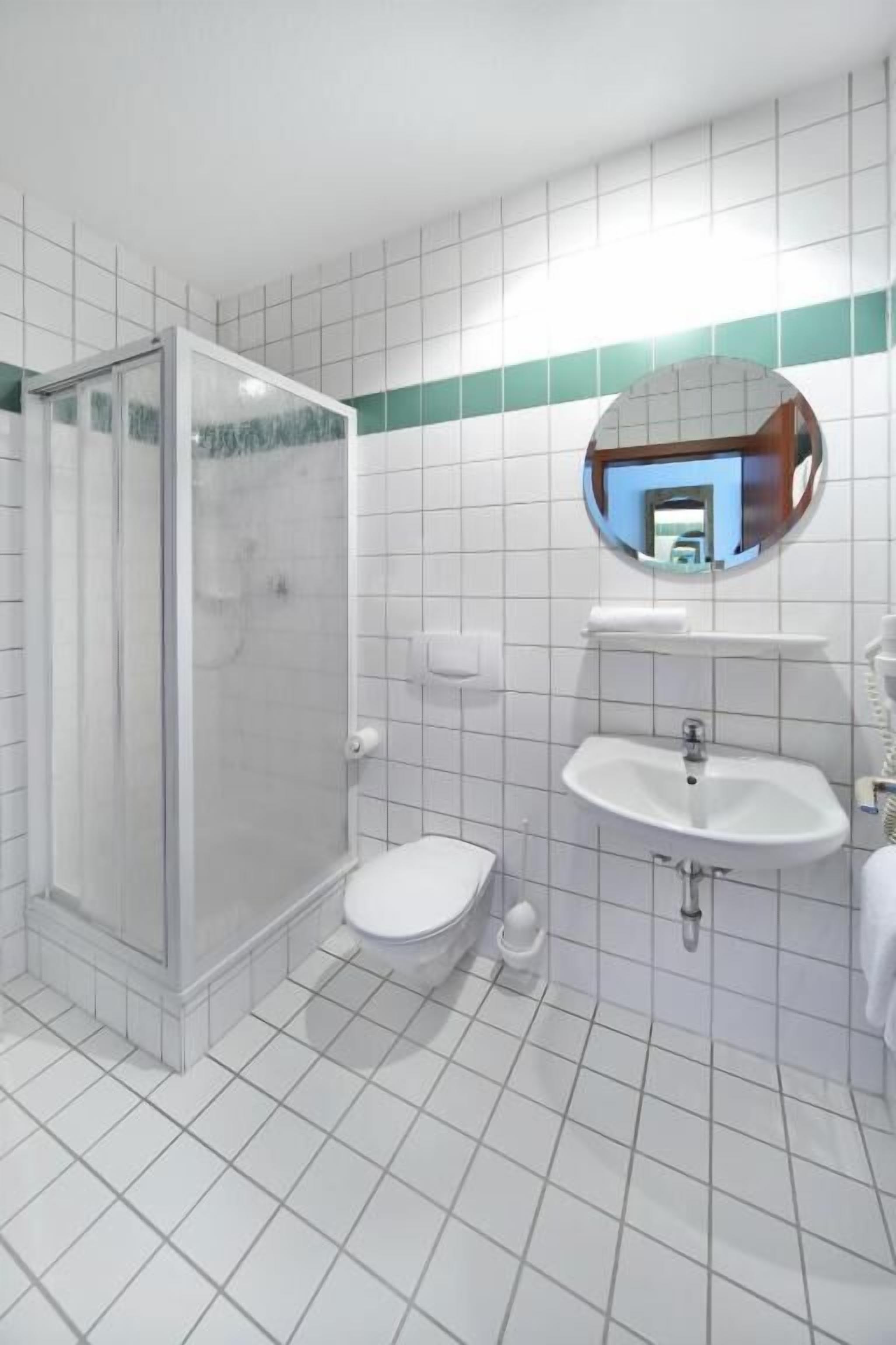 A bathroom with a glass-enclosed shower, a toilet, a sink, and a mirror.