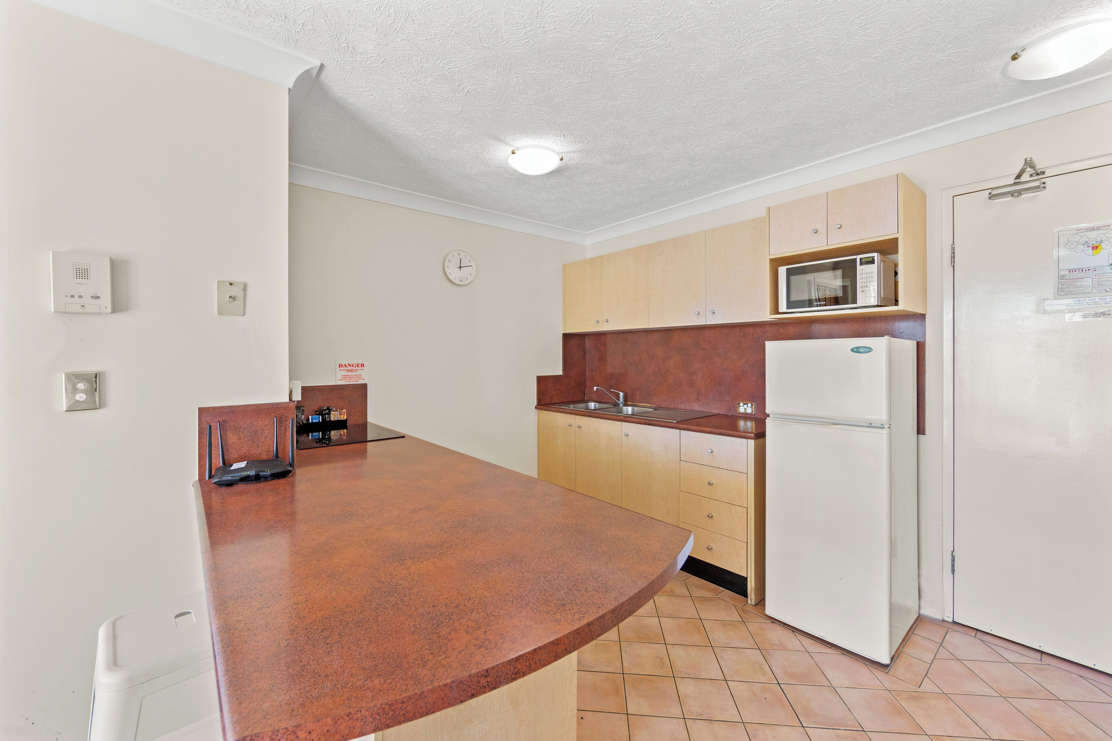 A kitchen with a brown countertop, white cabinets, a microwave, and a refrigerator.