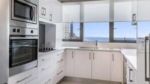 Una cocina moderna con electrodomésticos integrados, un ventanal y vistas a la ciudad.
