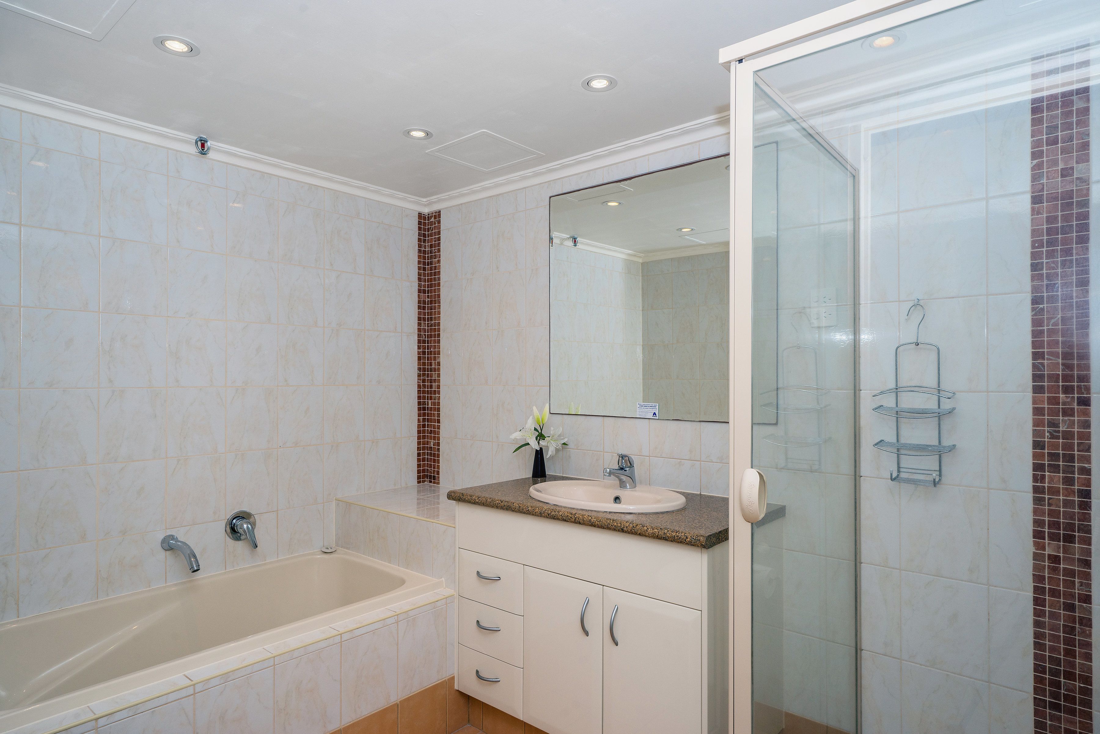 A bathroom with a bathtub, a sink, a mirror, and a shower area.