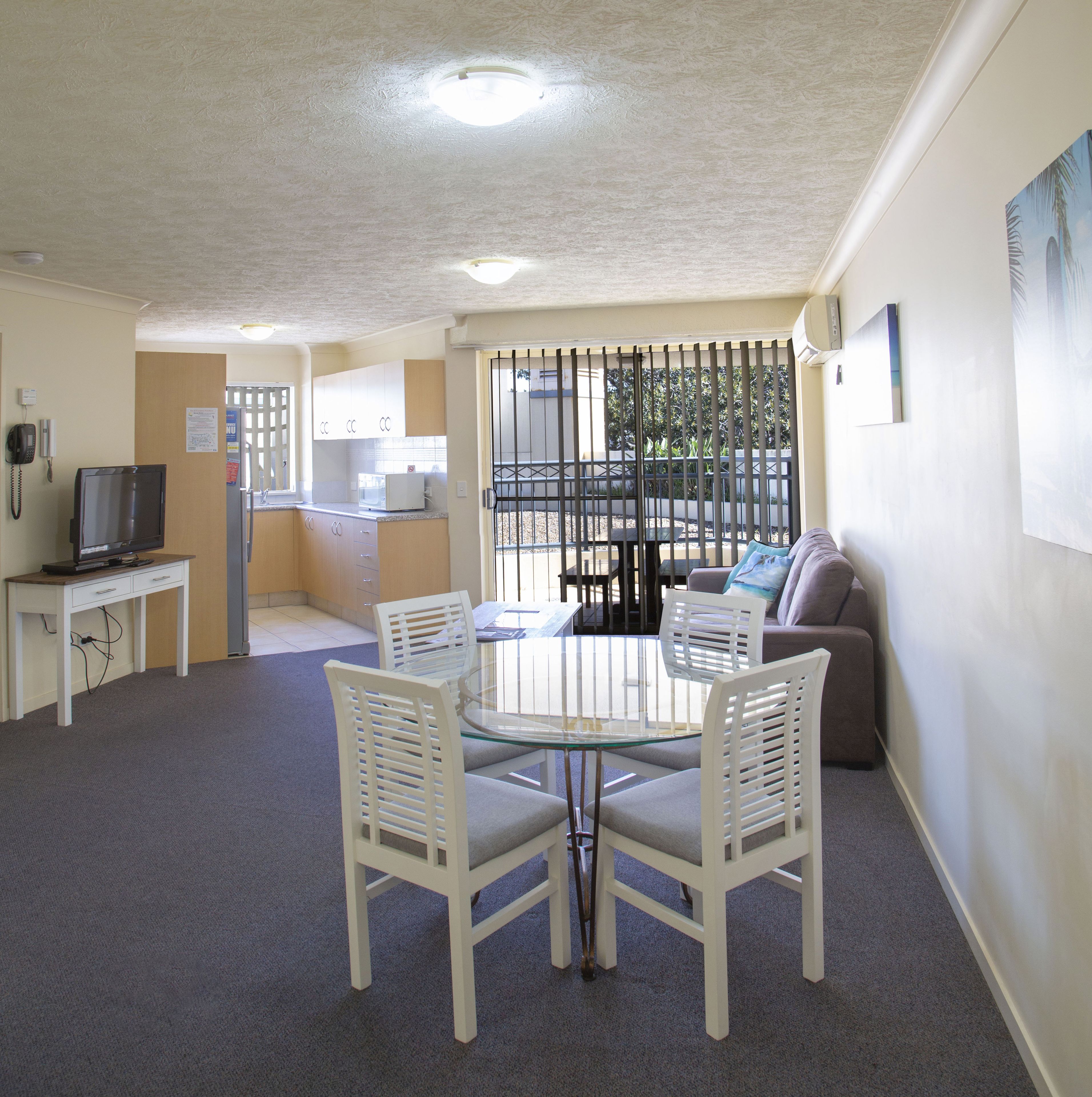 A compact living space with a dining area, kitchenette, and a seating area with a sofa and chairs.