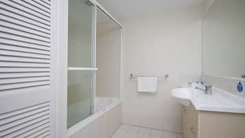 A bathroom with a bathtub, a sink, and a mirror.