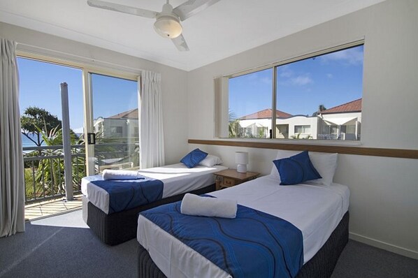 A hotel room with two beds, a balcony, and a view of the sea.