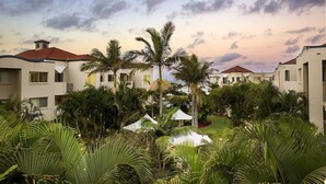 A resort with multiple buildings, palm trees, and a clear sky. - Golden Riviera Beach Resort (Tugun)