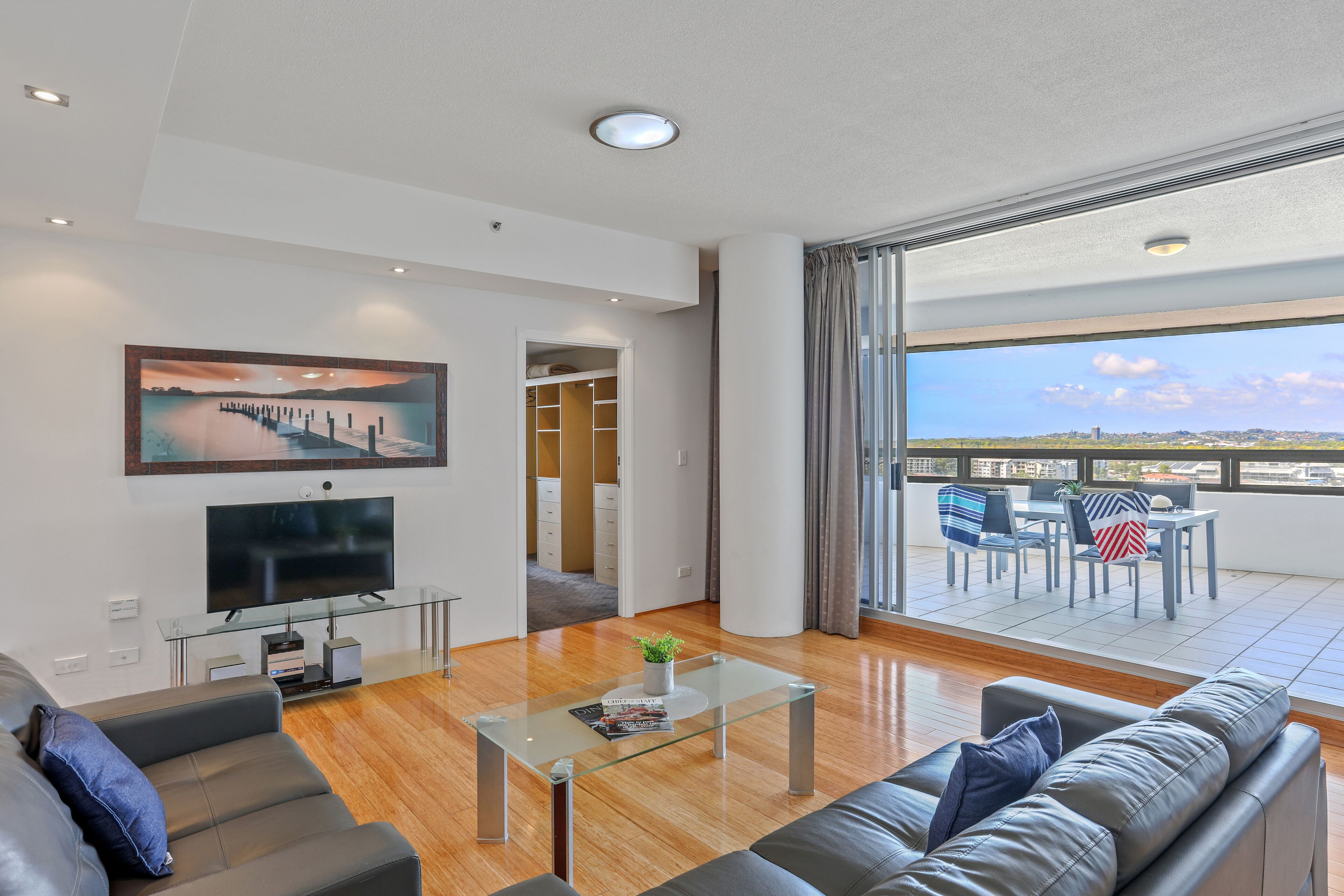Una sala de estar moderna con un televisor de pantalla plana, sofás de cuero, una mesa de centro de vidrio y un ventanal con vistas a la ciudad.