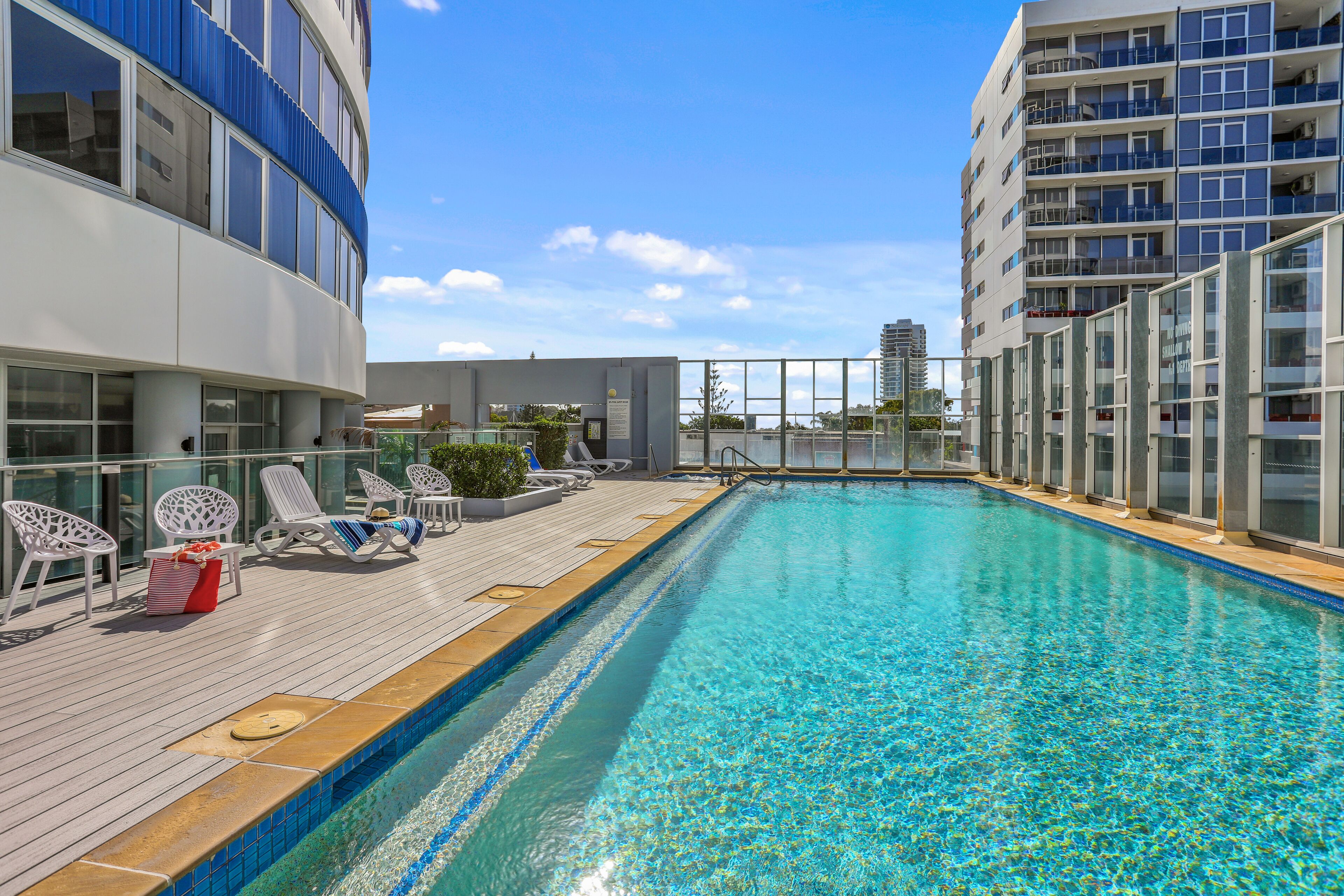 A rooftop pool with lounge chairs and a view of the city skyline.
