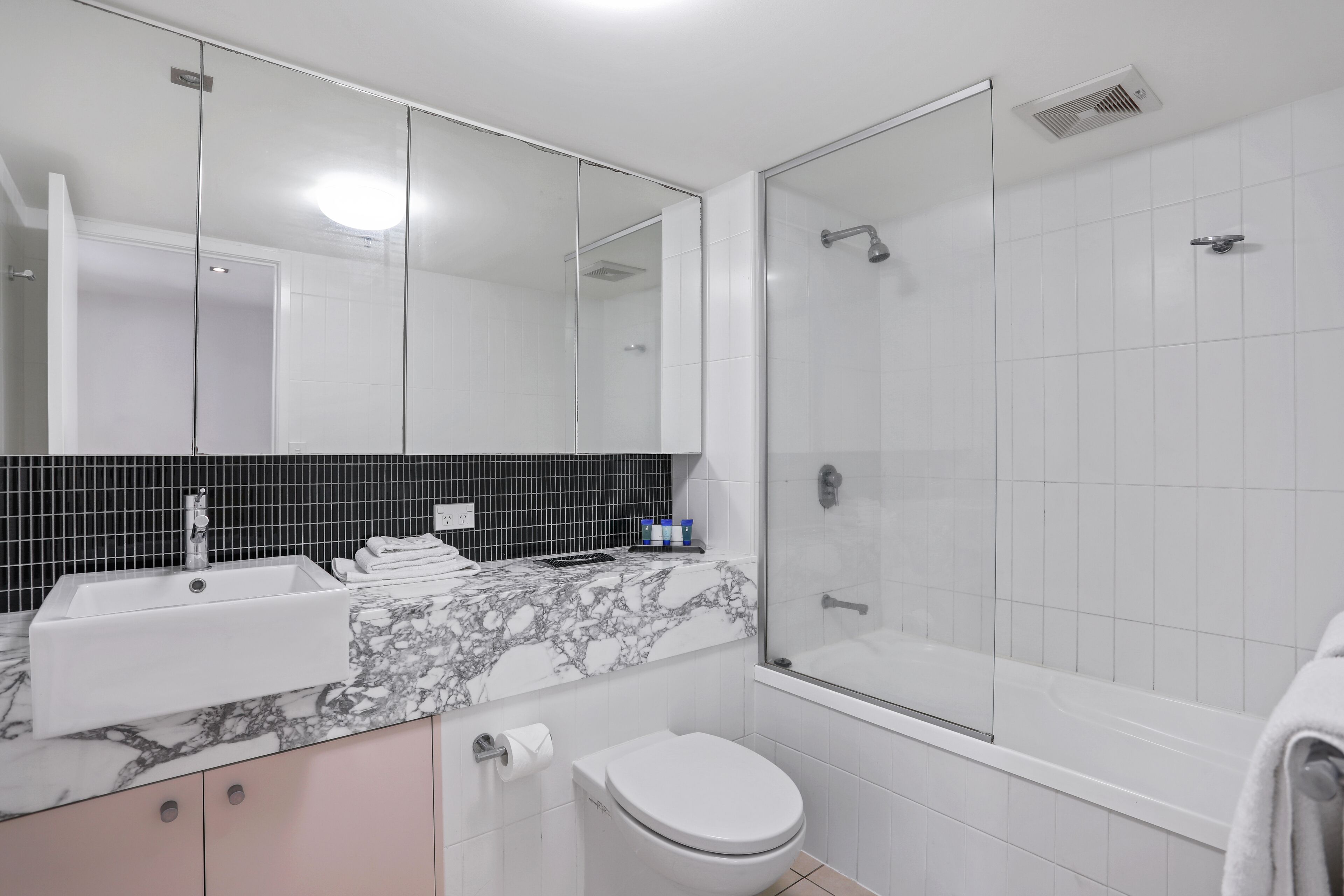 A modern bathroom with a glass-enclosed shower, a white sink, and a toilet.