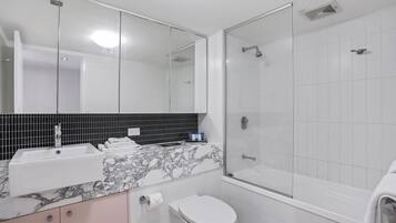 A modern bathroom with a glass-enclosed shower, a white sink, and a toilet.