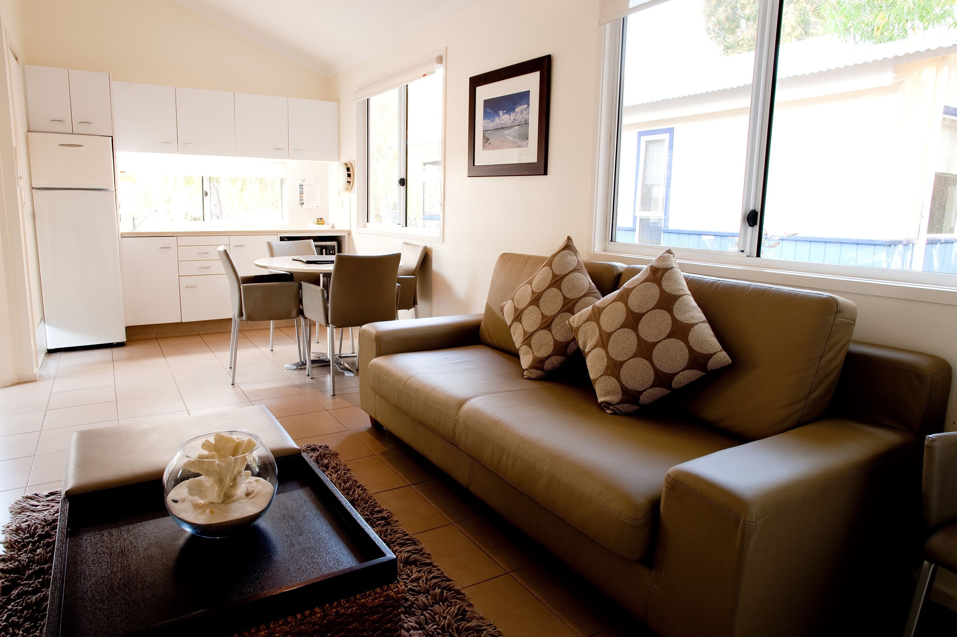 A modern living room with a sofa, a coffee table, and a dining area with chairs and a table.