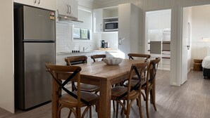 Eine moderne Küche mit weißen Schränken, einem Edelstahl-Kühlschrank, einem Holztisch und Stühlen.