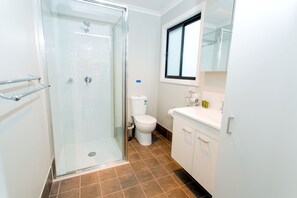 A bathroom with a glass-enclosed shower, a toilet, and a sink with a mirror above it. - BIG4 Tweed Billabong Holiday Park (Tweed Heads South)