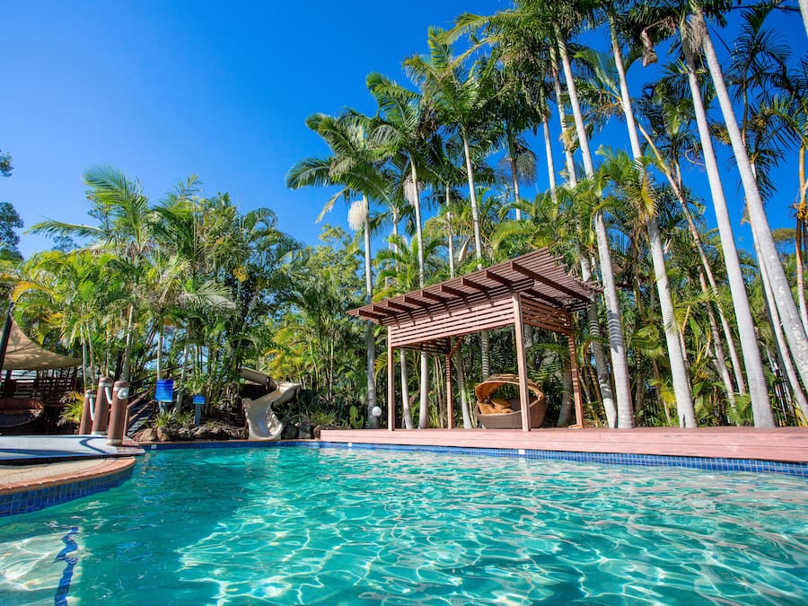 Una piscina al aire libre, sombrillas, sillones reclinables de piscina